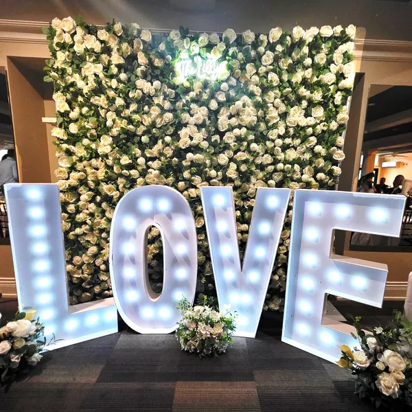 Illuminated LOVE letters in front of a white floral wall